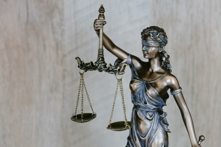 tingey-injury-law-firm-DZpc4UY8ZtY-unsplash Sculpture en bronze représentant une femme aux yeux bandés portant une balance.